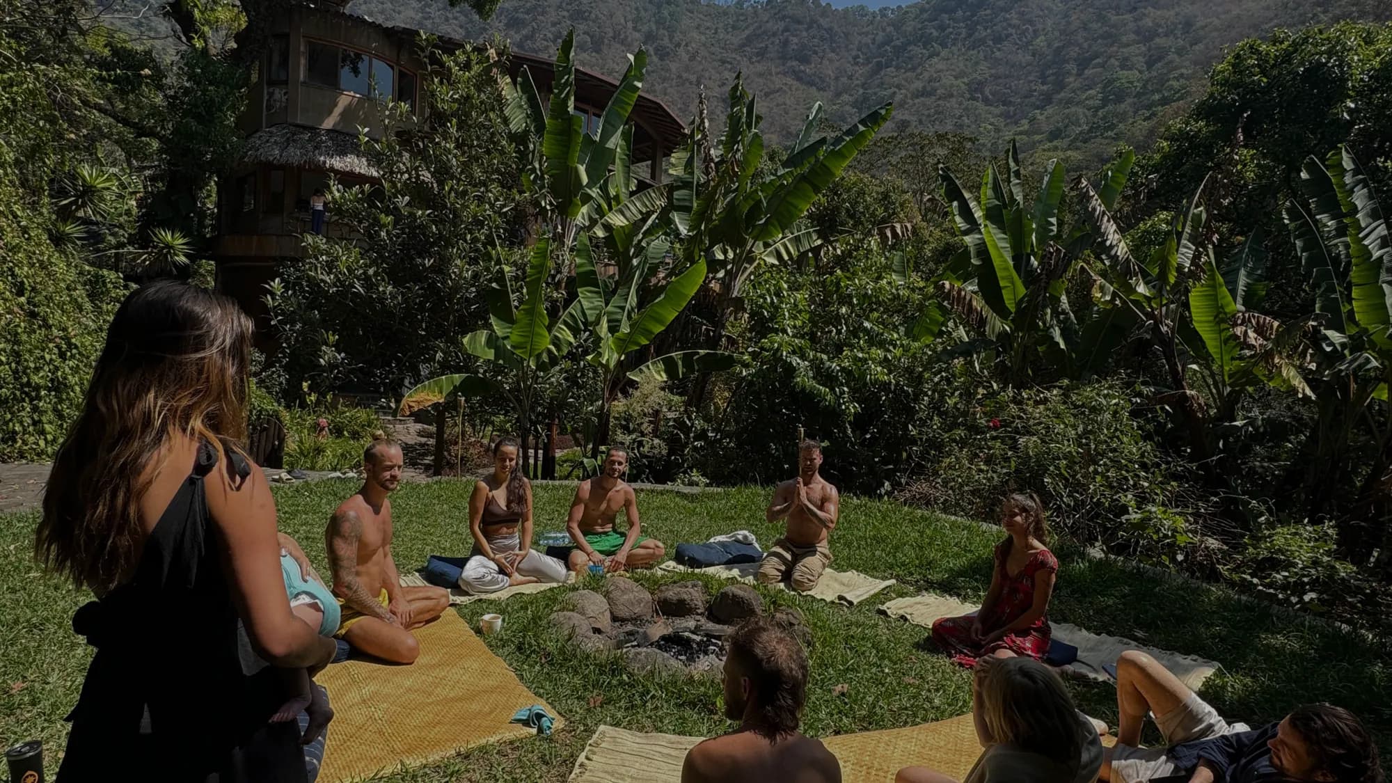 Guests sitting in a circle on mats on the grass at Maestro Valley, surrounded by jungle