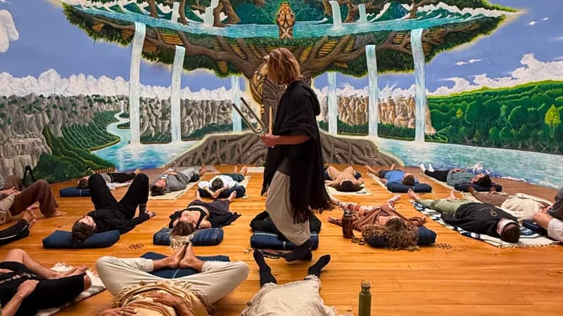 A host guiding guests lying on mats inside the painted sound dome