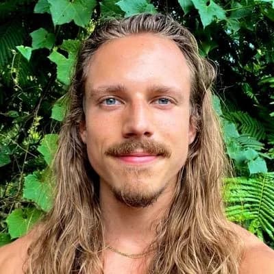 Christian Van Camp standing in front of tropical greenery
