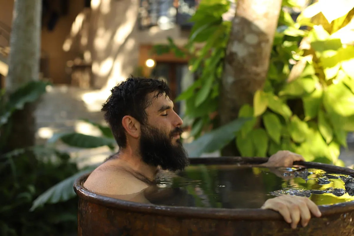 A retreat guest relaxing in an outdoor hot tub surrounded by greenery
