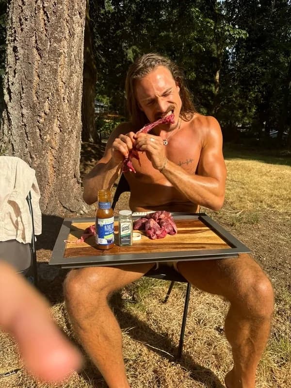 A man eating raw meat at a sunlit outdoor table