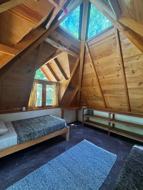 Shared double room beneath a wooden A-frame roof