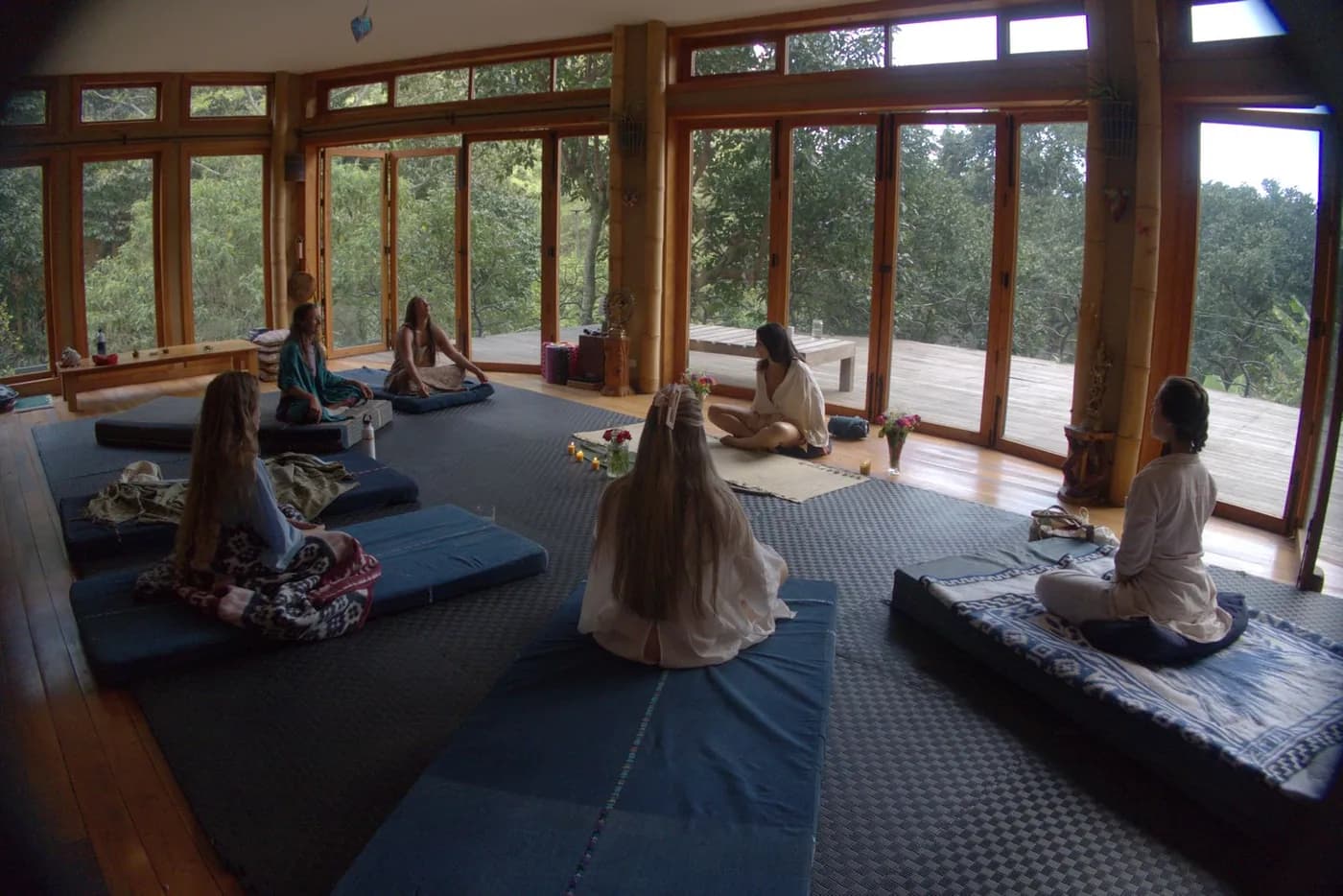 Women sitting in a circle on blue mats in the wood and glass studio