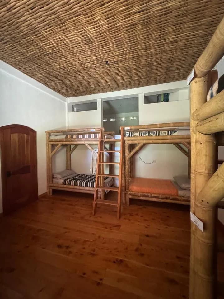 Bamboo bunk beds with wool blankets, a wooden ladder and an arched door