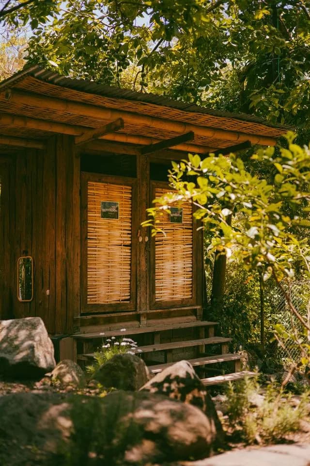 A wooden cabin with bamboo shutters among the trees