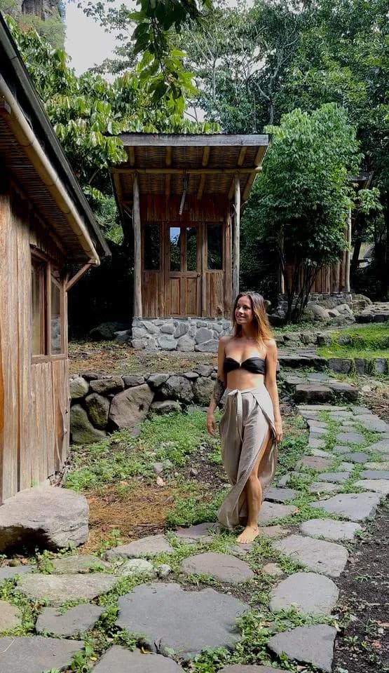 A woman walking along a stone path between wooden cabins