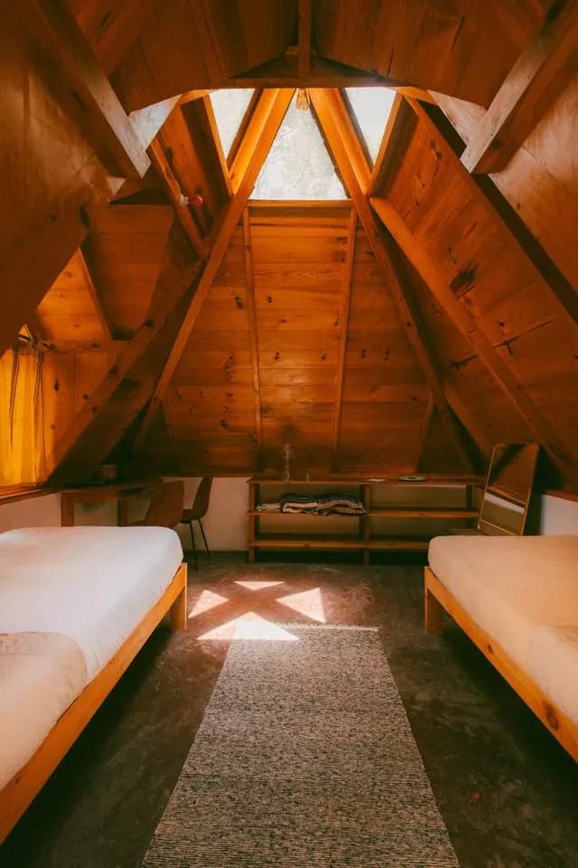 Two twin beds inside the wooden pyramid beneath a triangular skylight