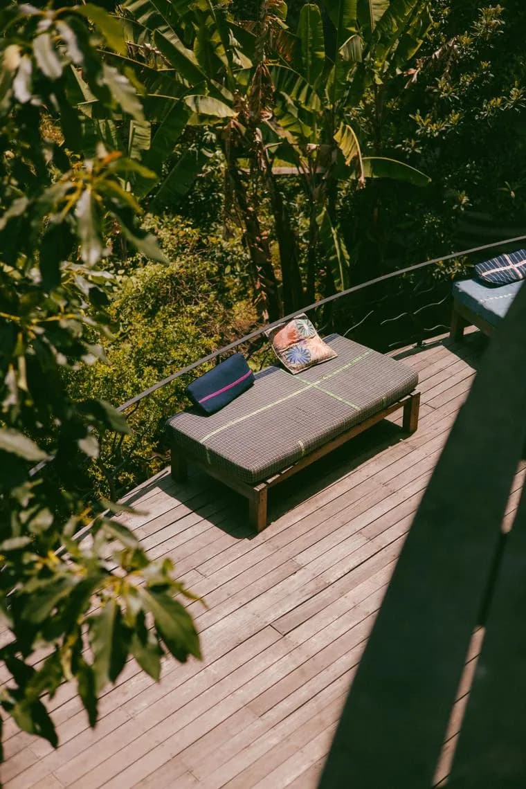 A lounge daybed on a sunny wooden deck among the trees