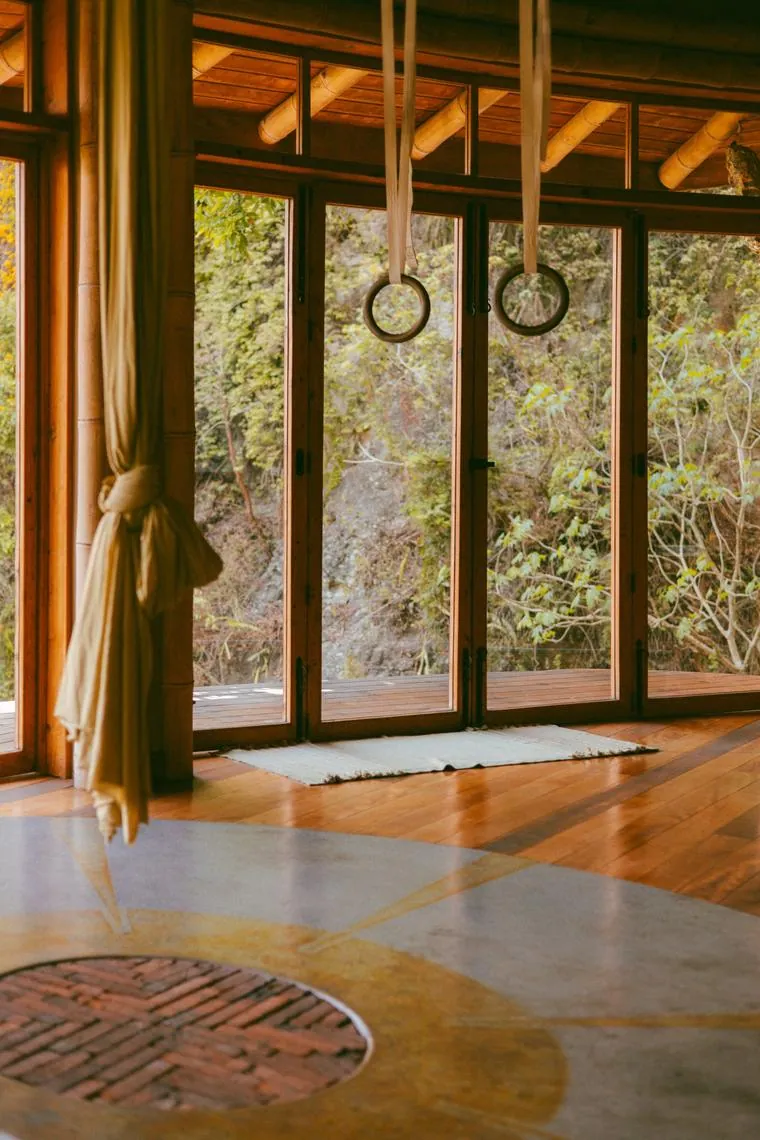 Aerial silks hanging in front of big studio windows, over a golden circle on the floor