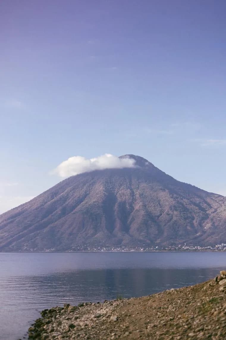 A volcano rising from the blue water of Lake Atitlán under a clear sky
