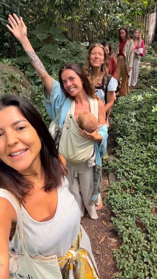 Sisters arriving along a garden path, one waving, one carrying her baby