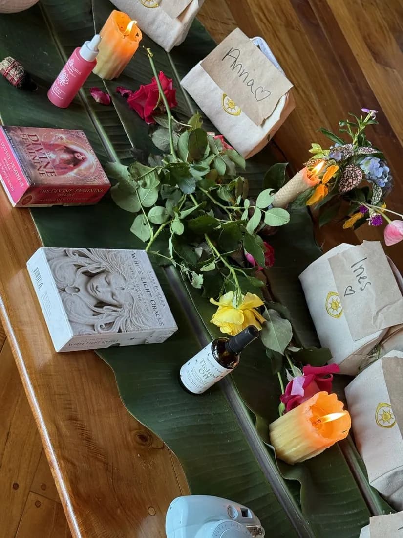 A welcome table on a banana leaf with candles, roses, oracle cards and named welcome bags