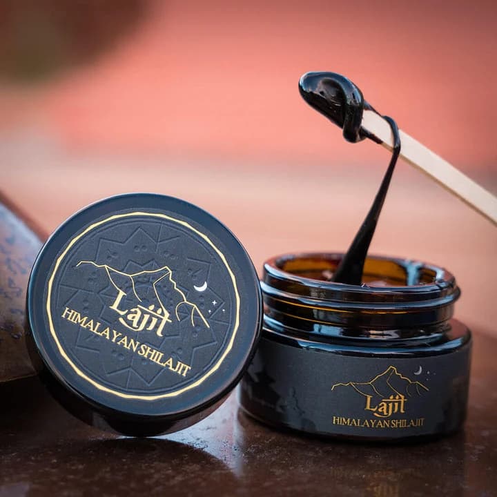 Lajit Shilajit resin jar and spoon against a warm sunset sky